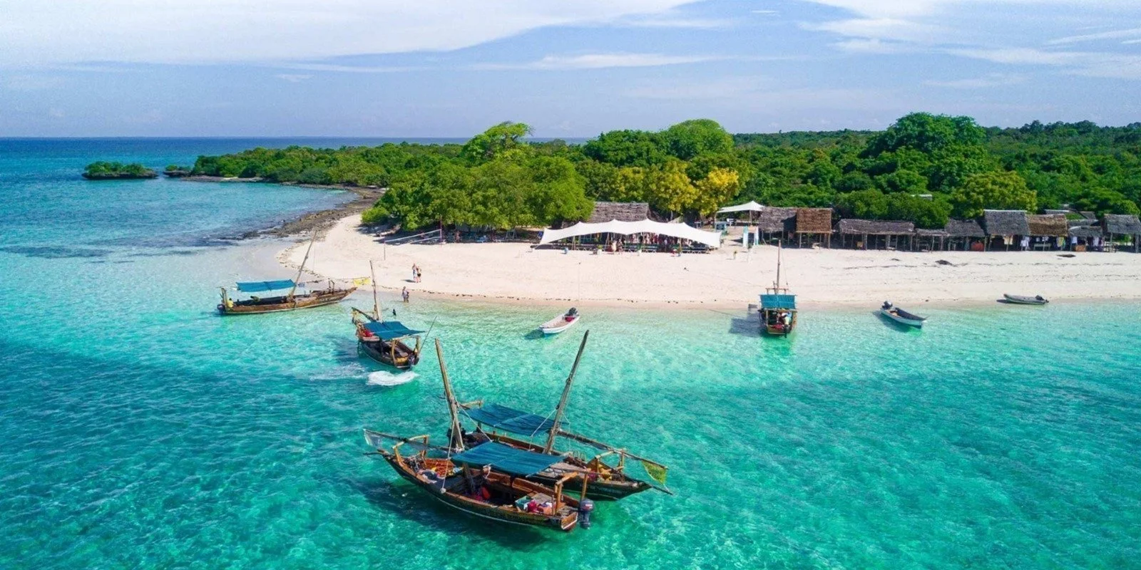 Traditional dhows anchored in turquoise shallows off a white-sand Zanzibar beach